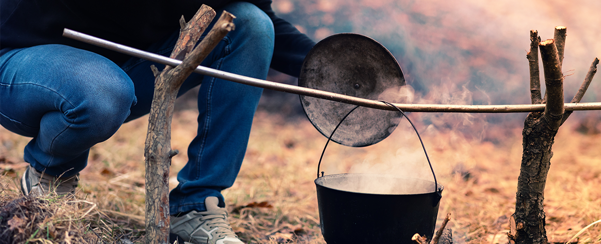 Man cooking with Dutch oven over campfire