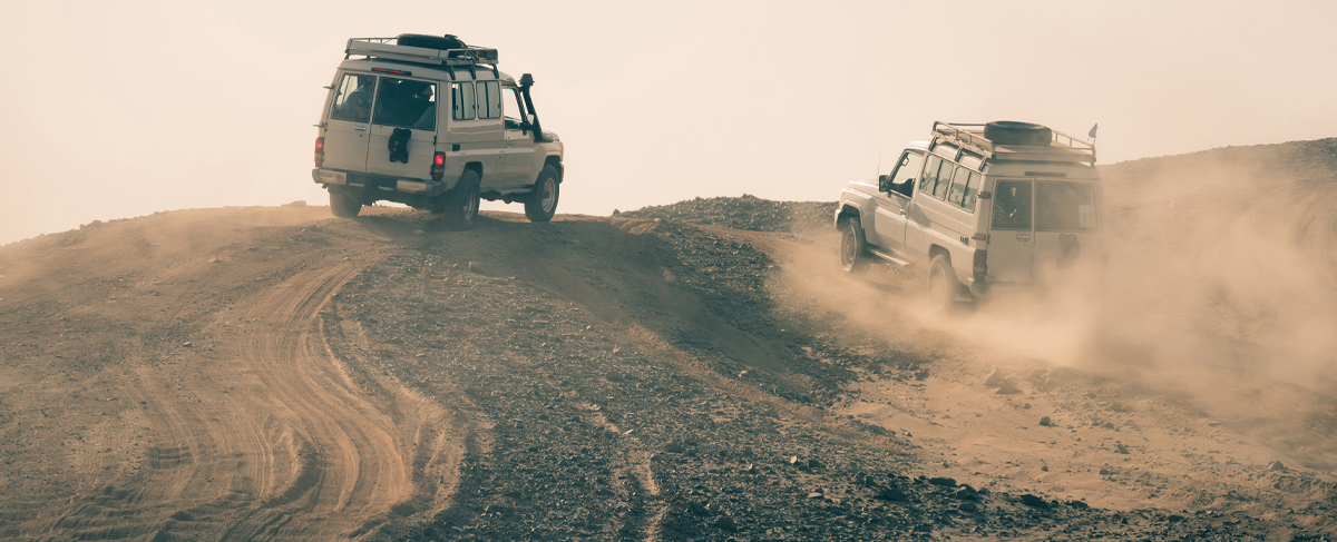 Two Land Rovers driving across desert terrain